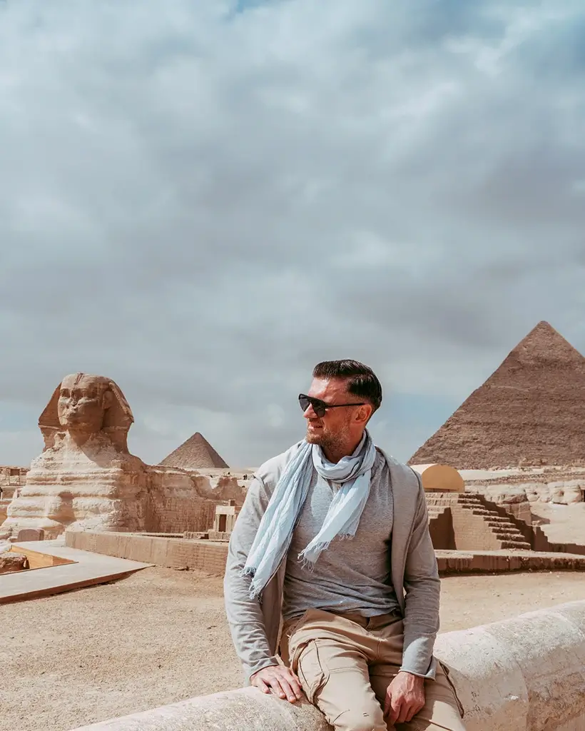 Professional Egyptologist guide explaining the history of the Great Pyramid of Giza to travelers during a guided Egypt pyramid tour