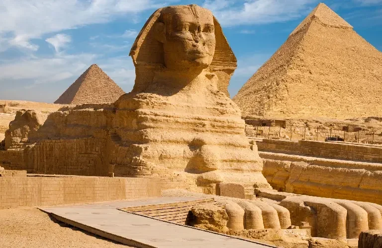 The Great Sphinx of Giza carved from natural limestone bedrock with the Pyramid of Khafre rising behind it on the Giza Plateau