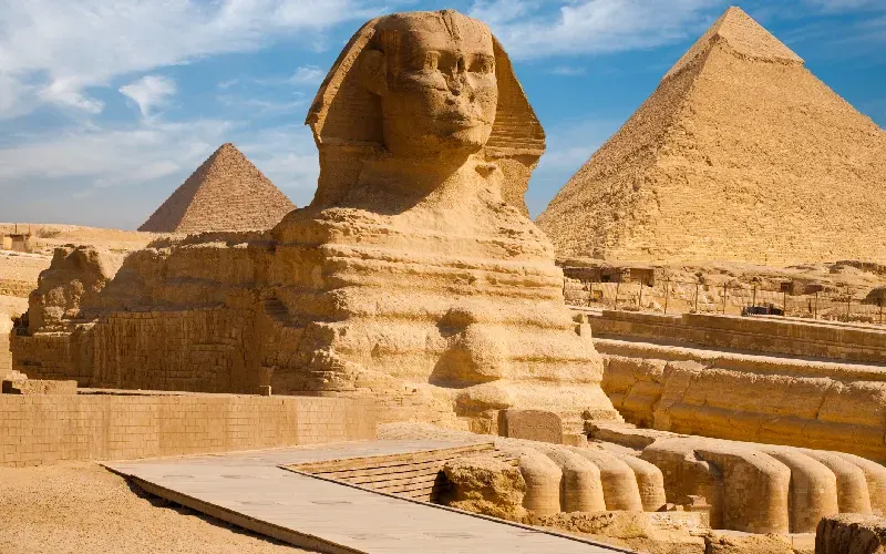 The Great Sphinx of Giza carved from natural limestone bedrock with the Pyramid of Khafre rising behind it on the Giza Plateau