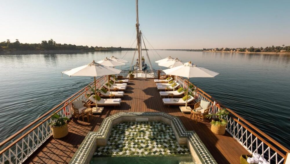 Nile River Cruise ship sailing past palm-fringed banks and desert hills between Luxor and Aswan