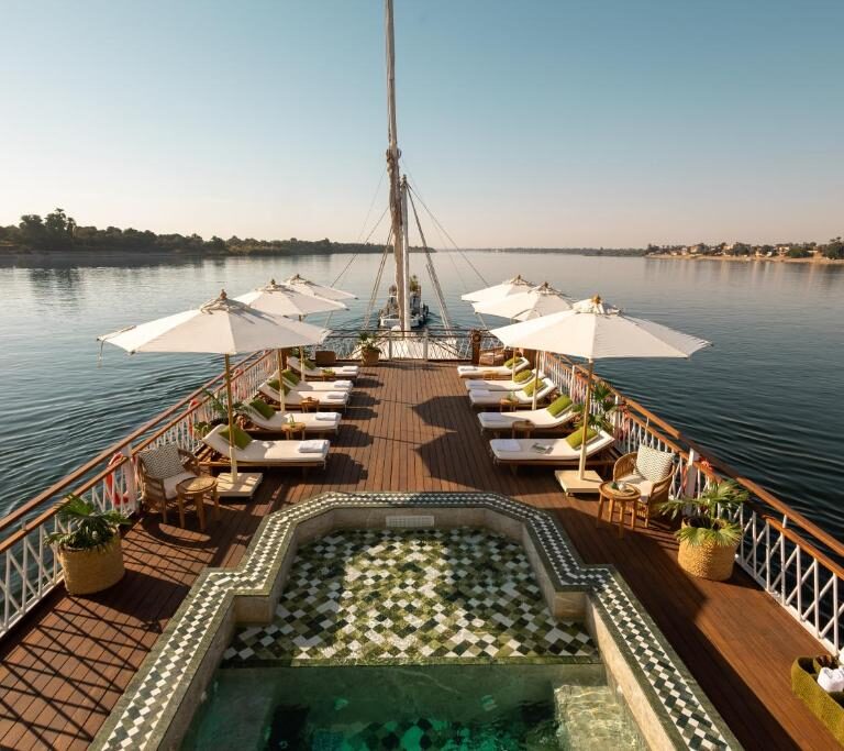 Nile River Cruise ship sailing past palm-fringed banks and desert hills between Luxor and Aswan