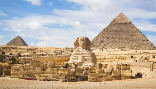 Within Egypt Tours a Wide panoramic view of the Giza Plateau showing the Great Sphinx in the foreground and the Pyramids of Khafre and Khufu rising behind it